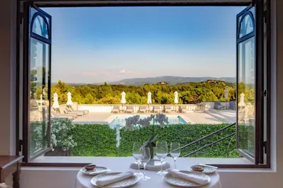 a table with a view of a pool through a window at Le Phébus & Spa – Relais & Châteaux in Joucas