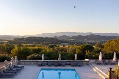 a pool with chairs and a view of the mountains at Le Phébus & Spa – Relais & Châteaux in Joucas
