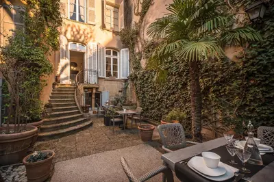an outdoor patio with tables and chairs and a building at Hôtel Particulier Le 28 - Spa & Art Luxury Design in Aix-en-Provence