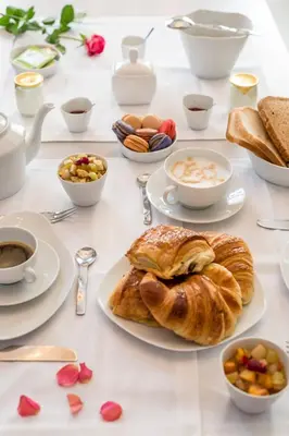 a table with plates of food and cups of coffee and croissants at Hôtel Particulier Le 28 - Spa & Art Luxury Design in Aix-en-Provence