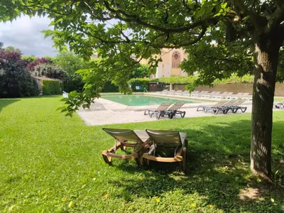 a group of chairs sitting in the grass under a tree at Hôtellerie Notre Dame de Lumières in Goult