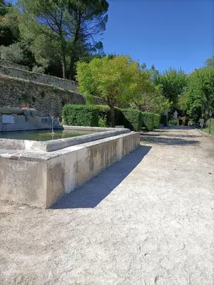 a stone bench with a fountain in a park at Hôtellerie Notre Dame de Lumières in Goult
