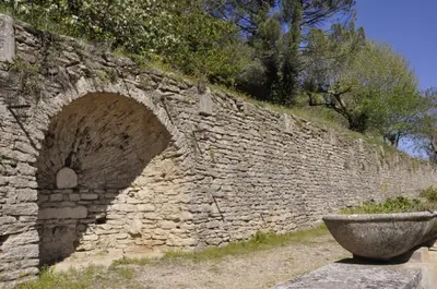a stone wall with a planter in front of it at Hôtellerie Notre Dame de Lumières in Goult