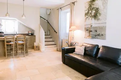 a living room with a leather couch and a kitchen at Le Mas De La Rose - Teritoria in Orgon
