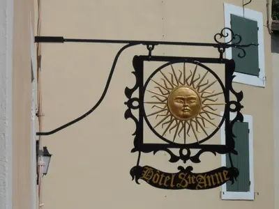 a sign with a gold head on the side of a building at Hotel Sainte Anne - Apt in Apt