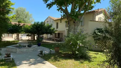 a large house with a tree in the yard at Mas des Cigognes in Le Thor
