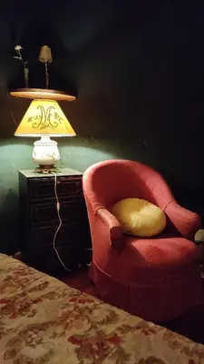 a red chair with a yellow pillow next to a lamp at Suite Provençale in Saignon
