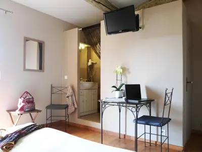 a bedroom with two chairs and a table with a laptop on it at Hotel Les Ambres in Roussillon