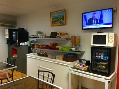 a kitchen with a tv on a wall with a refrigerator at Aix Hotel in Aix-en-Provence