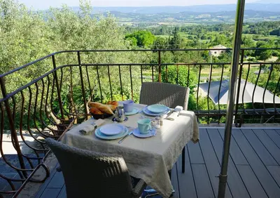 a table with plates and cups on a balcony at Les Terrasses du Luberon in Bonnieux