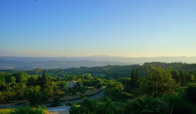 a view of a valley with trees and a road at Les Terrasses du Luberon in Bonnieux