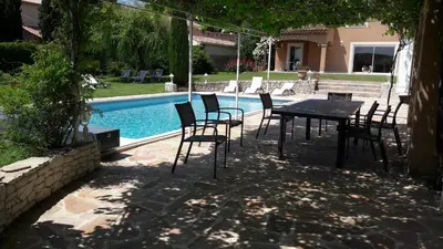 a table and chairs next to a swimming pool at Villa Eglantine in Caumont-sur-Durance