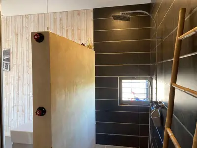 a bathroom with a shower with a black tile wall at Belle villa en Provence in Lançon-Provence