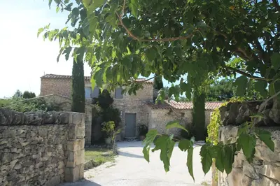 a stone house with a stone wall and a tree at Mas Oréa côté piscine in Gordes