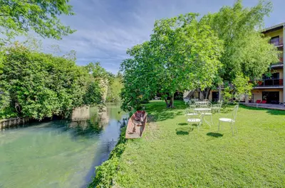 a boat on a river with tables and chairs at Hotel Les Nevons in LʼIsle-sur-la-Sorgue