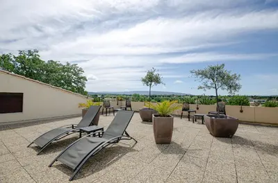 a group of chairs and tables on a patio at Hotel Les Nevons in LʼIsle-sur-la-Sorgue