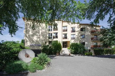 a large building with a lot of plants in front of it at Hotel Les Nevons in LʼIsle-sur-la-Sorgue