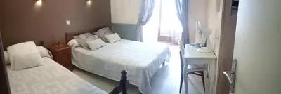 a bedroom with two beds and a small table and a window at Hotel Font De Lauro in Saumane-de-Vaucluse