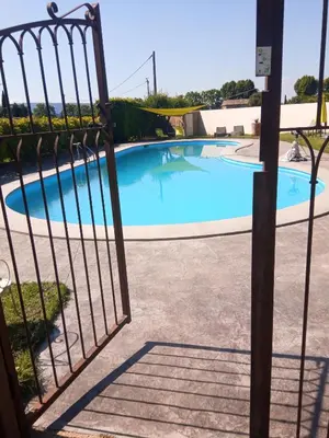 a gate leading to a swimming pool through a fence at Hotel Font De Lauro in Saumane-de-Vaucluse