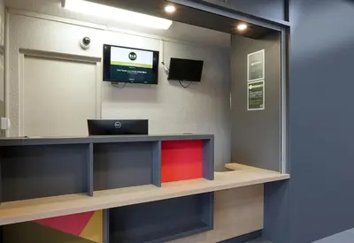 a reception desk with a laptop and a tv on a wall at B&B HOTEL Aix-en-Provence Pont de l'Arc in Aix-en-Provence
