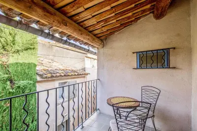 a patio with a table and chairs on a balcony at Maison de village in Bonnieux