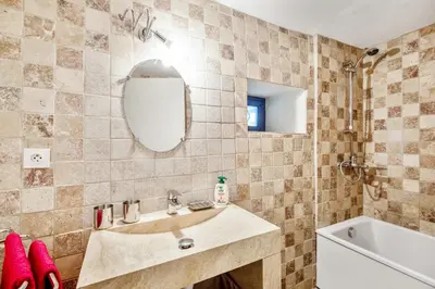 a bathroom with a sink and a tub and a mirror at Maison de village in Bonnieux
