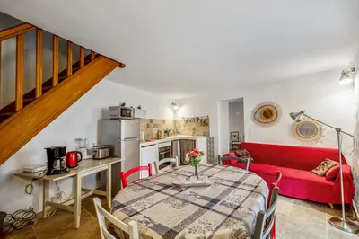 a living room with a table and a red couch at Maison de village in Bonnieux