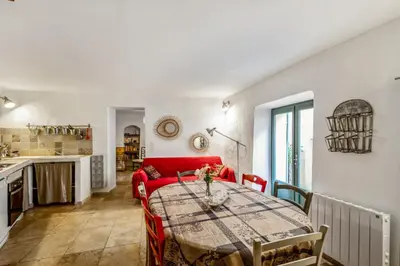 a living room with a red couch and a table at Maison de village in Bonnieux