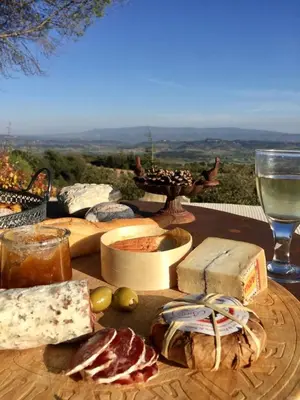 a wooden table topped with cheese and meats and a glass of wine at Mas La Bellevue in Murs
