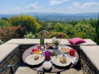 a table with plates of food and a bottle of wine at Mas La Bellevue in Murs