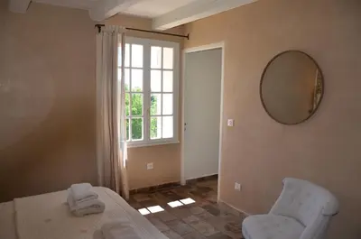 a room with a bed and a mirror and a window at Le Jas des Parpaillous in LʼIsle-sur-la-Sorgue