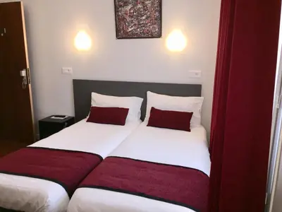a bedroom with two beds with red and white pillows at Hôtel Vendôme in Aix-en-Provence
