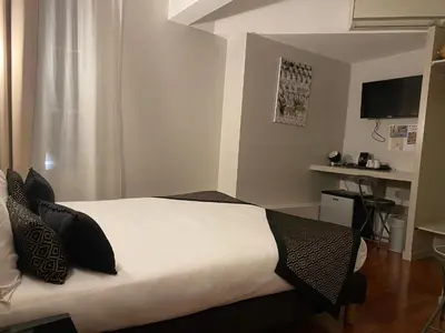 a bedroom with a bed with white sheets and black pillows at Hôtel Vendôme in Aix-en-Provence