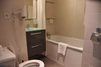 a bathroom with a white tub and a sink and a shower at Adonis Arc Hotel Aix in Aix-en-Provence