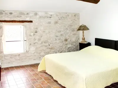 a bedroom with a bed and a stone wall at Maison de charme à Mollégès avec piscine privée in Mollégès