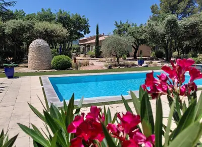 a pool with pink flowers in front of a house at Mas Val-Chênaie Gordes in Gordes