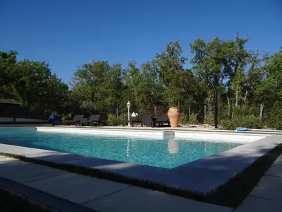 a swimming pool with blue water in a yard at Mas Val-Chênaie Gordes in Gordes
