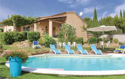 a pool with chairs and an umbrella and a house at 4 Bedroom Beautiful Home In Goult in Goult