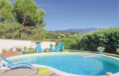 a swimming pool with two chairs and a table at 4 Bedroom Beautiful Home In Goult in Goult