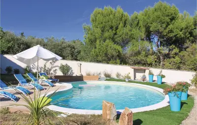 a swimming pool in a yard with chairs and an umbrella at 4 Bedroom Beautiful Home In Goult in Goult