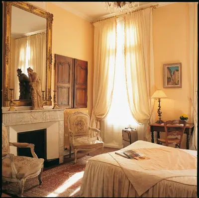 a bedroom with a bed and a mirror and a fireplace at Hotel Cardinal in Aix-en-Provence