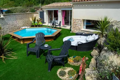 a backyard with a pool and two chairs and a table at L instant Magique in Beaumont-de-Pertuis