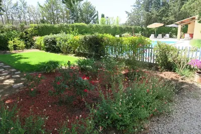 a garden with flowers and a fence and a pool at Villa - La Luberonne in Lourmarin