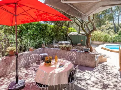 a table with a red umbrella next to a pool at Apartment Mireio by Interhome in Lambesc
