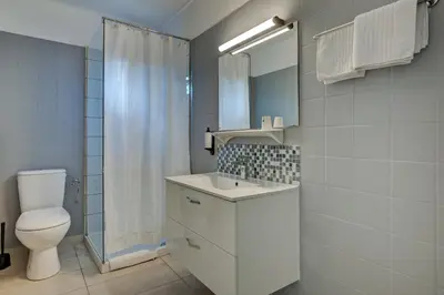 a white bathroom with a toilet and a sink at Hôtel Paul in Aix-en-Provence