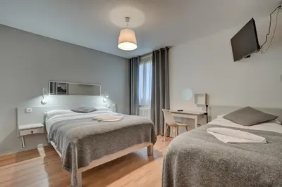 a bedroom with two beds and a desk and a television at Hôtel Paul in Aix-en-Provence