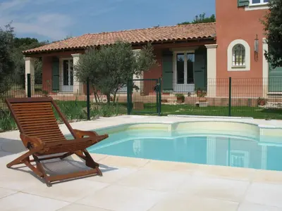 a wooden chair sitting next to a swimming pool at Ll POULIDETTO in Lioux