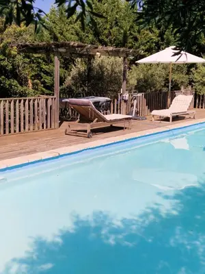 a swimming pool with two chairs and an umbrella at The Neame House in Bédoin