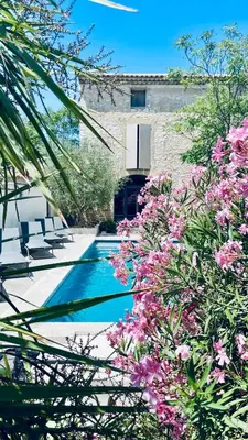 a swimming pool with pink flowers in front of a building at Le Mas du Félibre in Caumont-sur-Durance