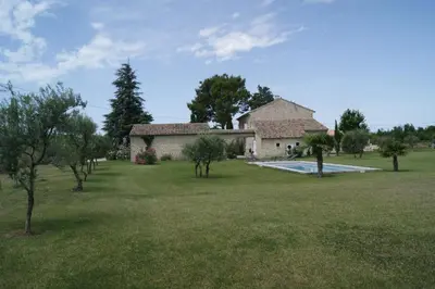 a house with a yard with a swimming pool and trees at Gîtes dans Mas en pierres in Robion en Luberon